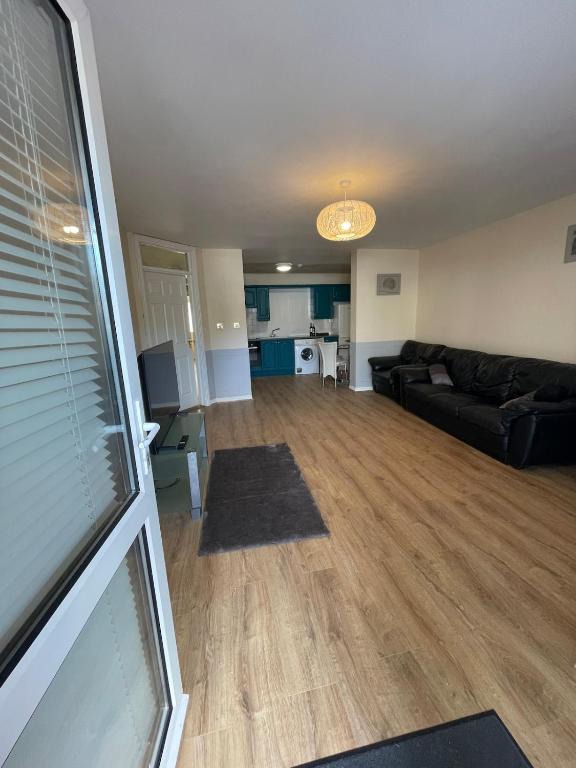 a living room with a black couch and a kitchen at Modern Town Centre 3 Bed Apartment in Sligo