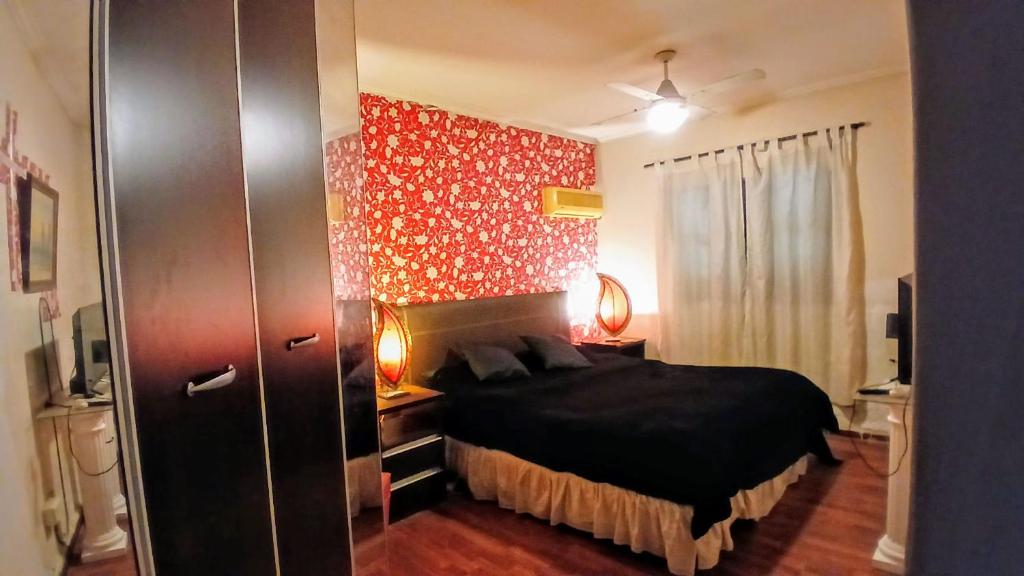a bedroom with a black bed and a red wall at Temporario balcarce in Santo Tomé