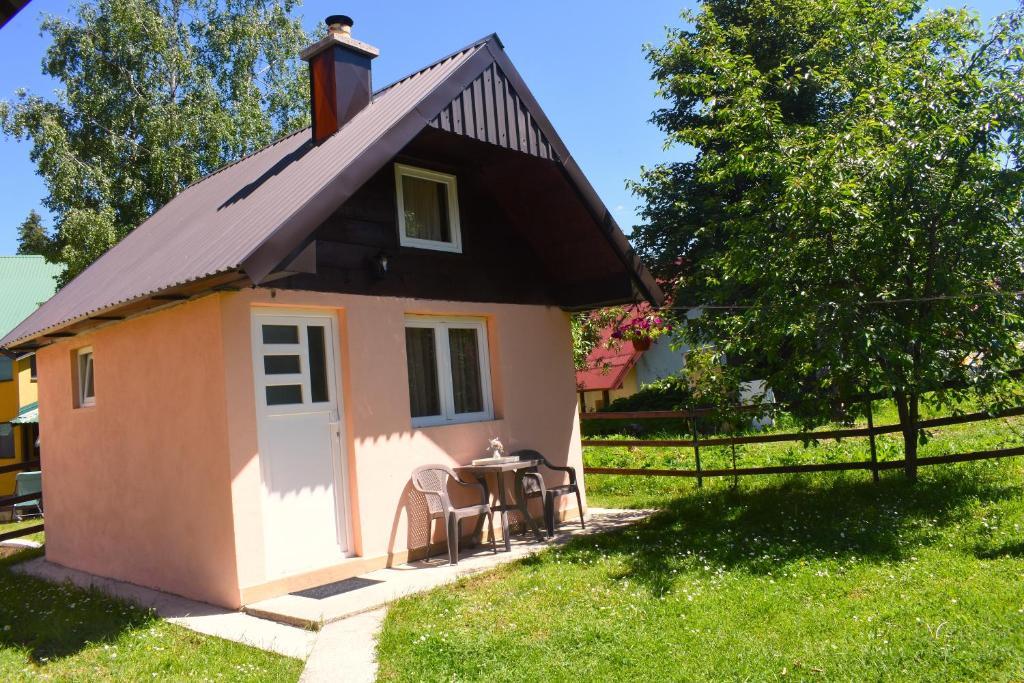 a small pink house with a table in the grass at Durmitorski san in Žabljak