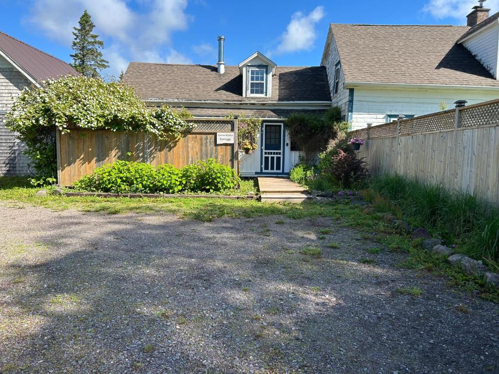 a house with a wooden fence and a driveway at Quaco Cottages-The Shipbuilder's Summer Kitchen in Saint Martins