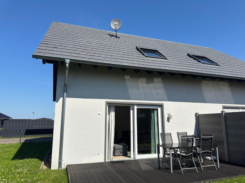 a house with a deck with chairs and a table at Moderne Ferienwohnung mit Sauna & Terrasse in Burhave