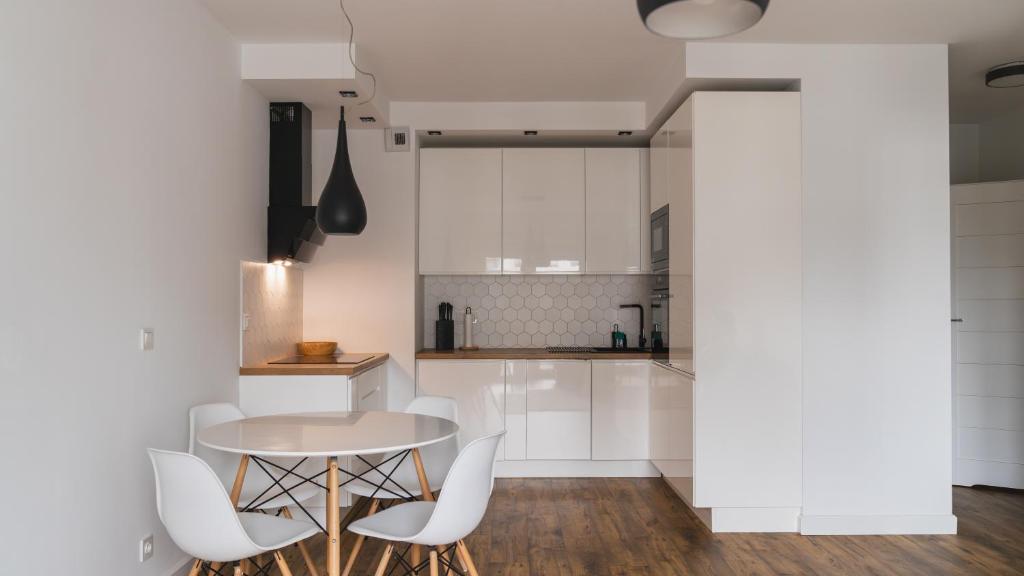 a kitchen with white cabinets and a table and chairs at BEMO Apartment in Warsaw