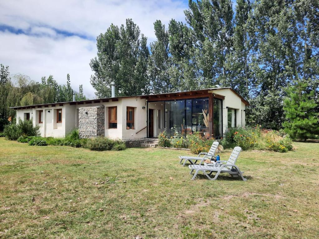 a house with two lawn chairs in front of it at Tafi del Valle Casa Kabure in Tafí del Valle