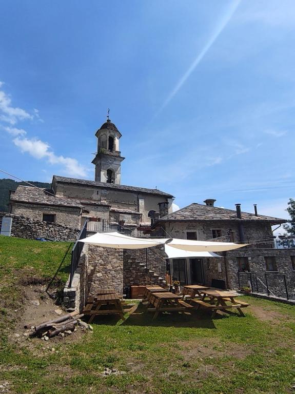 an old stone building with picnic tables and a tower at Rifugio in Voga in Gordona