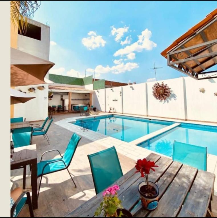 a swimming pool with a wooden table and chairs at HOTEL LAS FUENTES in Tepotzotlán