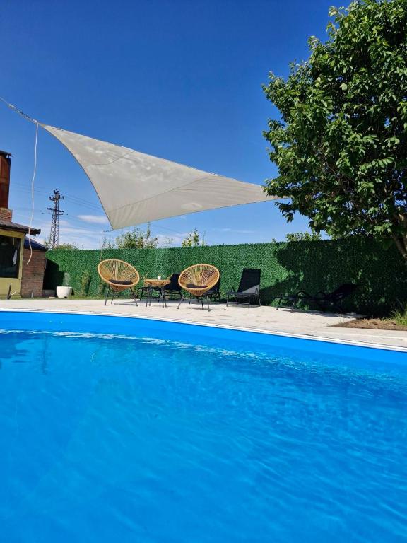 two chairs and a white umbrella over a swimming pool at Diamond House Rent -vikendica sa privatnim bazenom in Beška