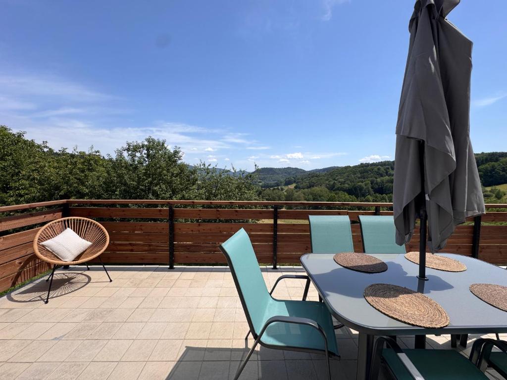 a patio with a table and chairs and an umbrella at Gîte la Tinou in Saint-Nabord