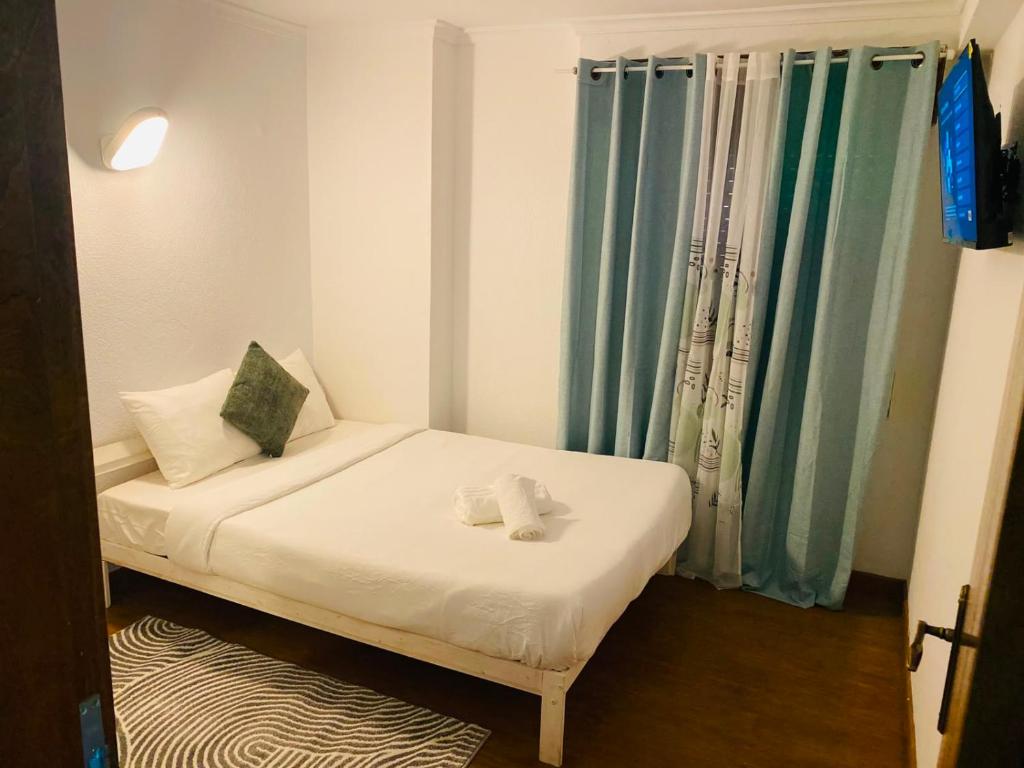 a small bed in a room with blue curtains at London Guest House in Caneças
