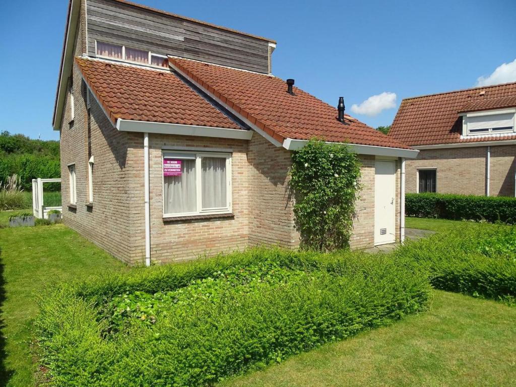 a house with a ivy growing on the side of it at Bungalow in Breskens near Beach and Lighthouse in Breskens