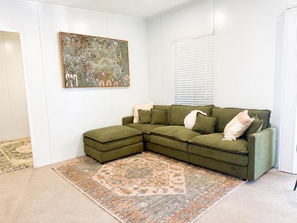 a living room with a green couch and a rug at Gem on Matrix - Hidden Retreat with Deck in Lightning Ridge