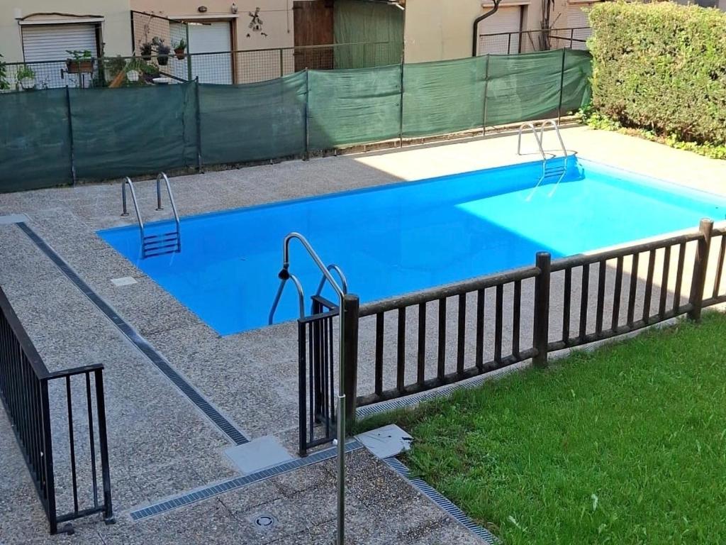a large blue swimming pool next to a fence at Hostal Casa Juan in Castejón de Sos