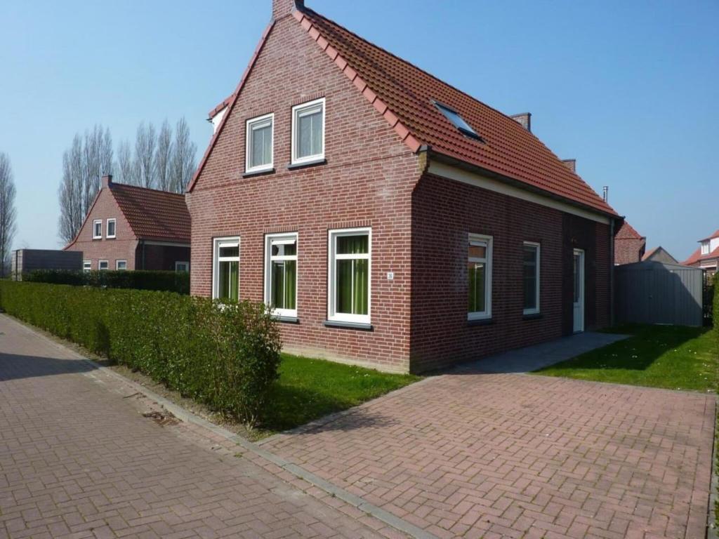 a red brick house with white windows on a street at Holiday Home Breskens near the Coast in Breskens
