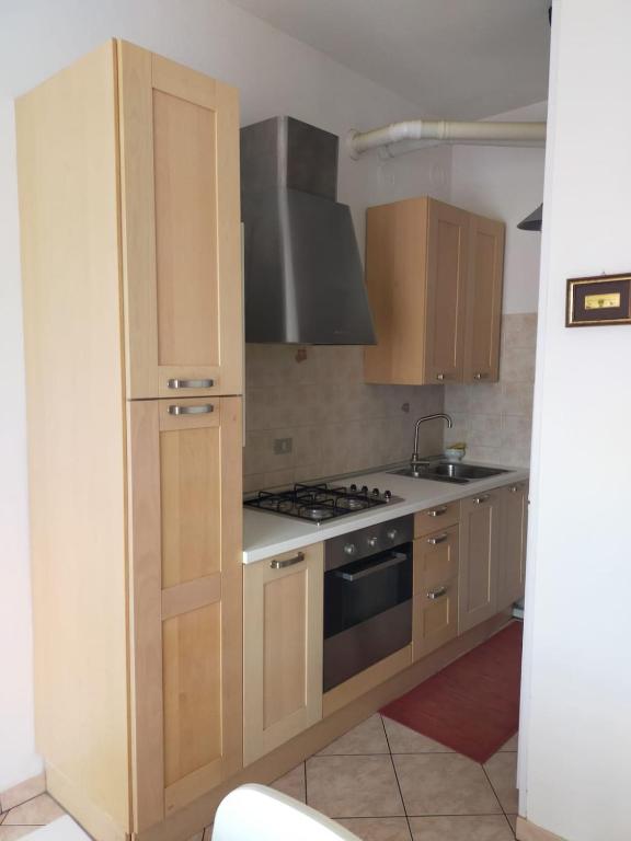 a kitchen with wooden cabinets and a stove at The sisters apartment in Punta Marina