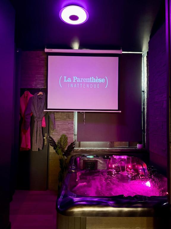 a sign in a room with a tub with purple lighting at La Parenthèse - Jacuzzi - Cinéma - Hyper-Centre in Bourges