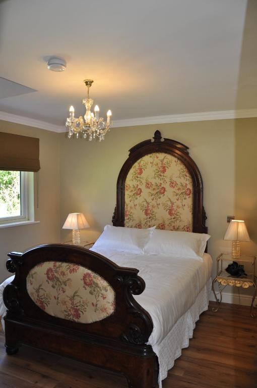 a bedroom with a large bed and a chandelier at Sheiling Accommodation in Castlemartyr