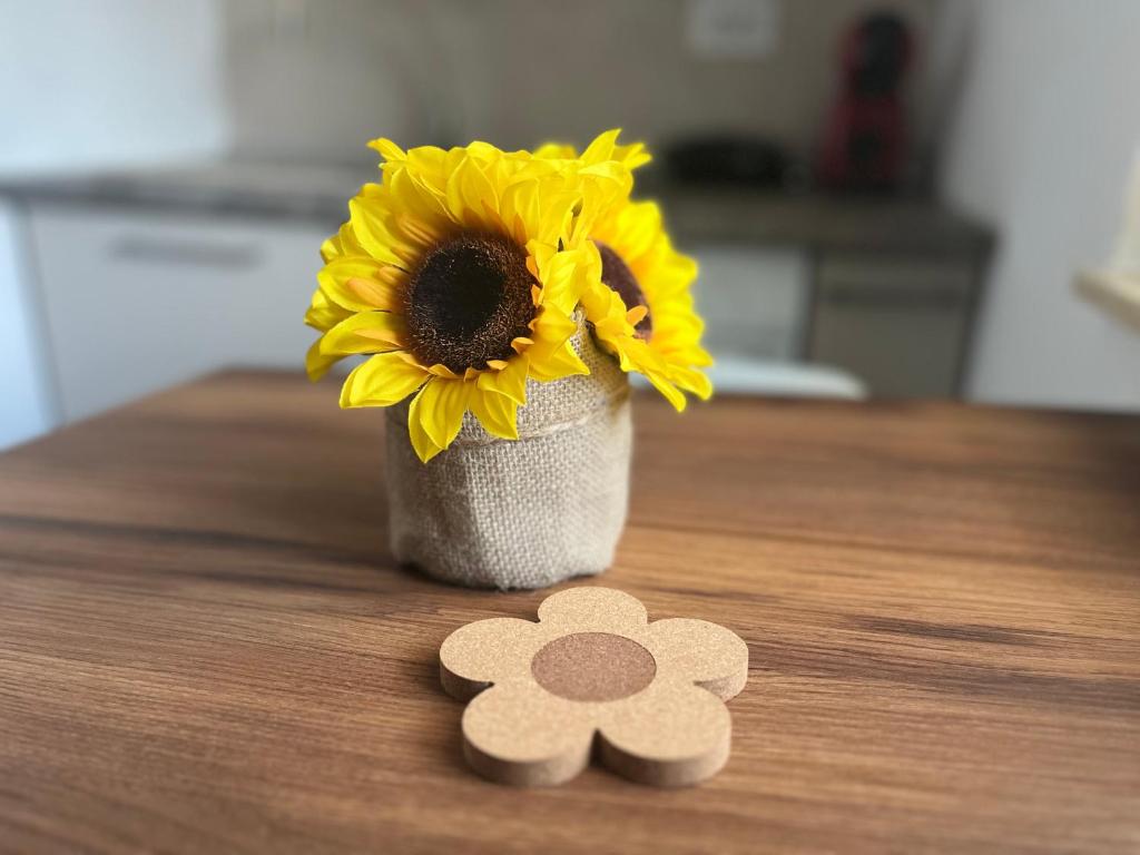 a vase filled with sunflowers sitting on a table with two wooden picks at Lena Apartment in Calafat