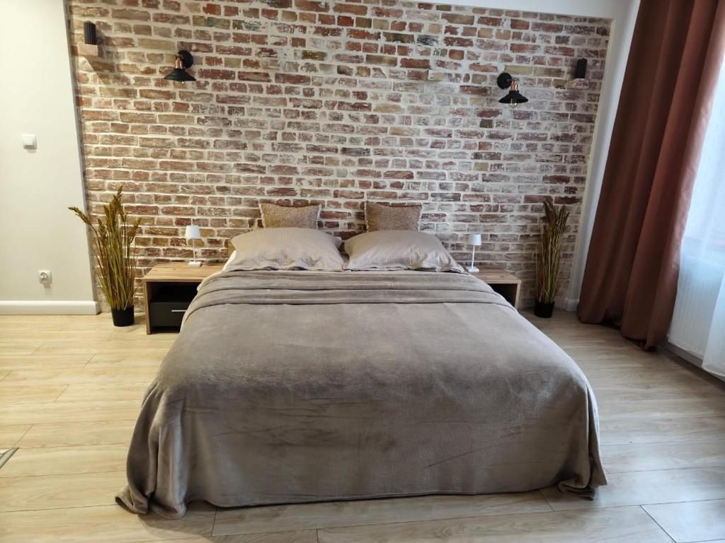 a large bed in a room with a brick wall at 1904 Studio in Świnoujście