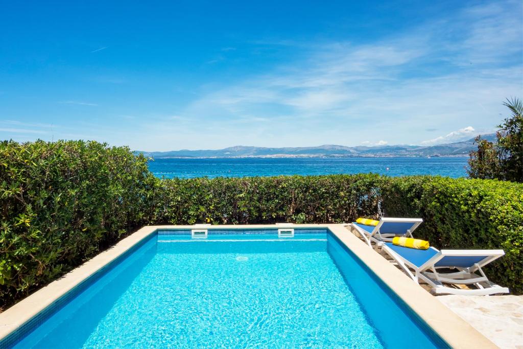 a swimming pool with two chairs and the ocean at Villas Violet & Rosemary in Supetar