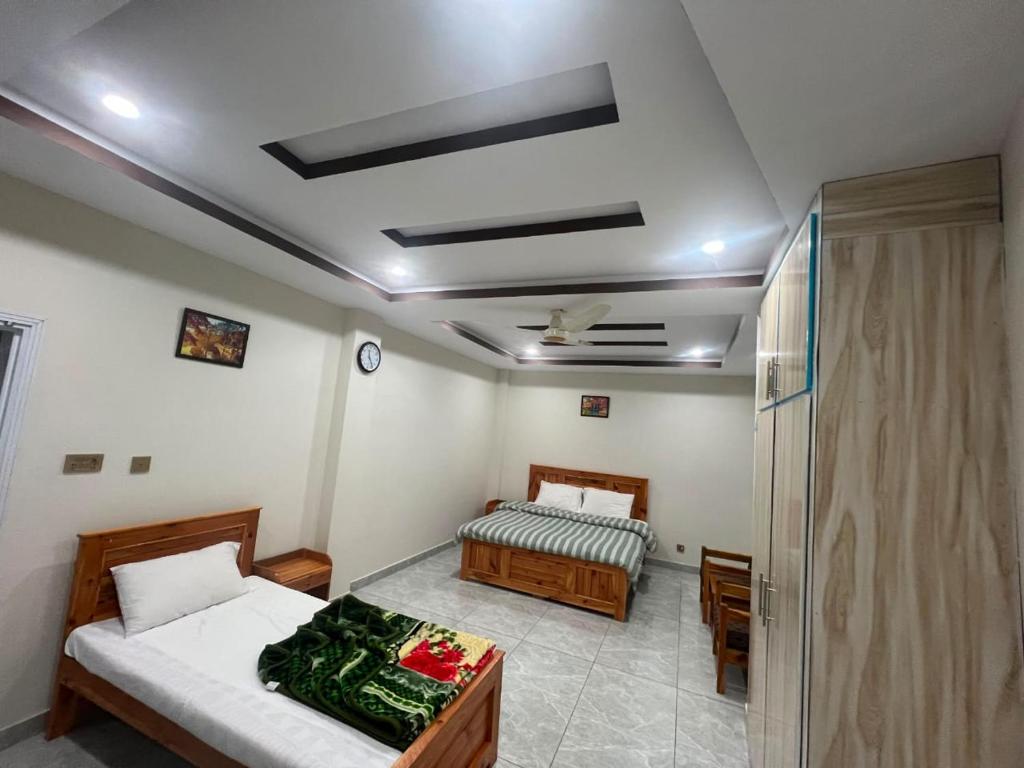 a bedroom with two beds and a table in it at Ember Guest House in Abbottabad