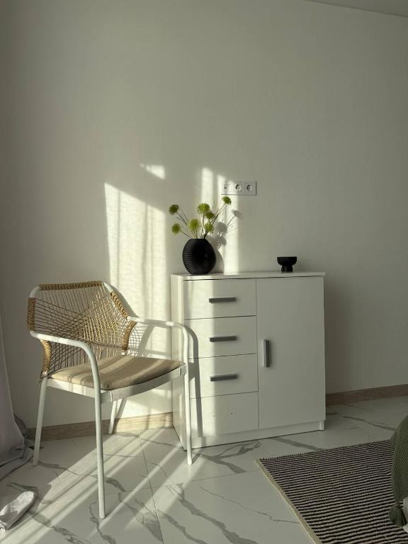 a white dresser and a chair in a room at Смарт хаус in Yuzhne
