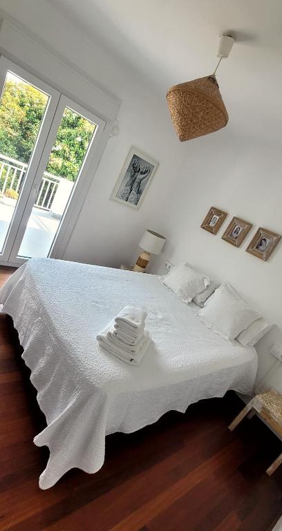 a white bed in a room with a window at Villa Pepe, casa compartida in Pontevedra