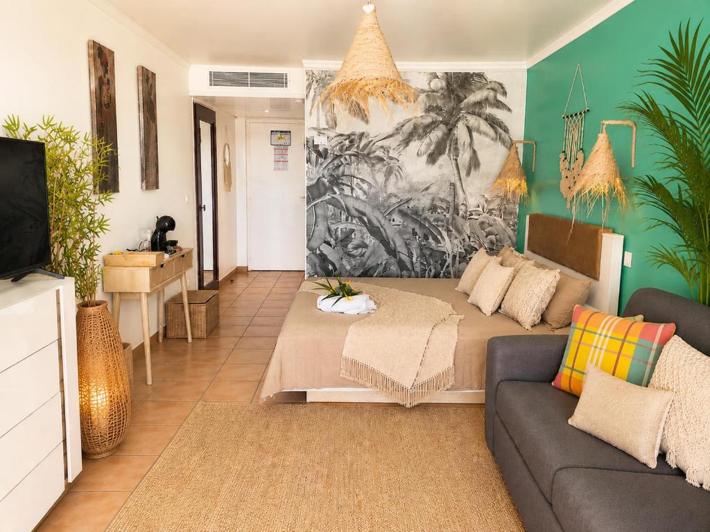 a living room with a couch and a tv at Couleur Caraïbes-TI EVASION appartement dan un village club 3 étoiles vue mer in Sainte-Luce