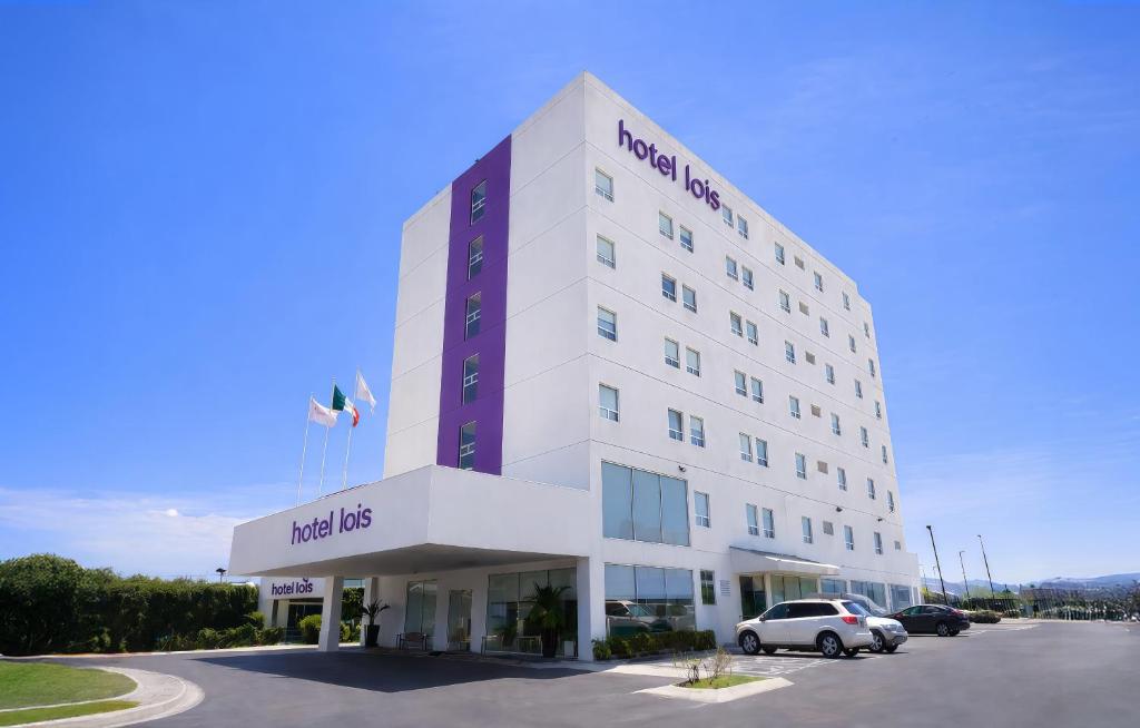 a hotel building with a car parked in a parking lot at Hotel Lois Express Monterrey Aeropuerto La Fe in Monterrey