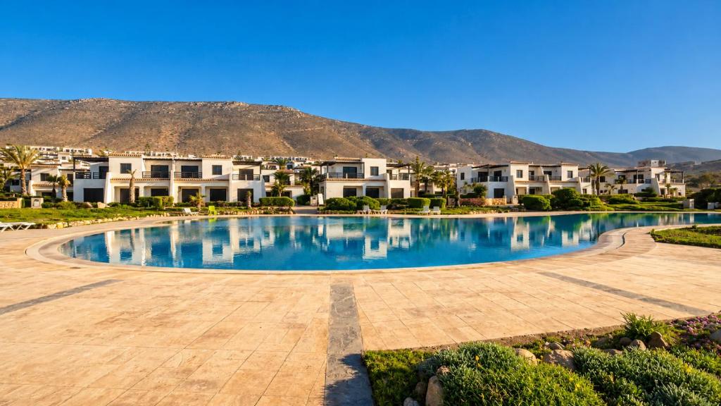 a large swimming pool with houses in the background at Villa Aglou Center in Zaouia Sidi Ouaggag