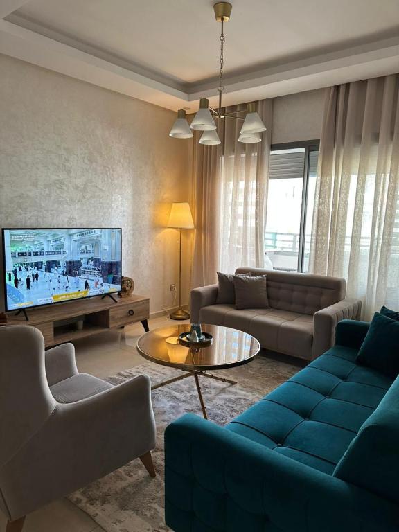 a living room with a blue couch and a tv at Appartement Confortable en Résidence Privée avec Piscine in Pont Blondin
