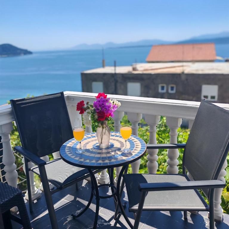 a table with two chairs and a vase of flowers on a balcony at ĆOSIĆ APARTMANI IGRANE in Igrane