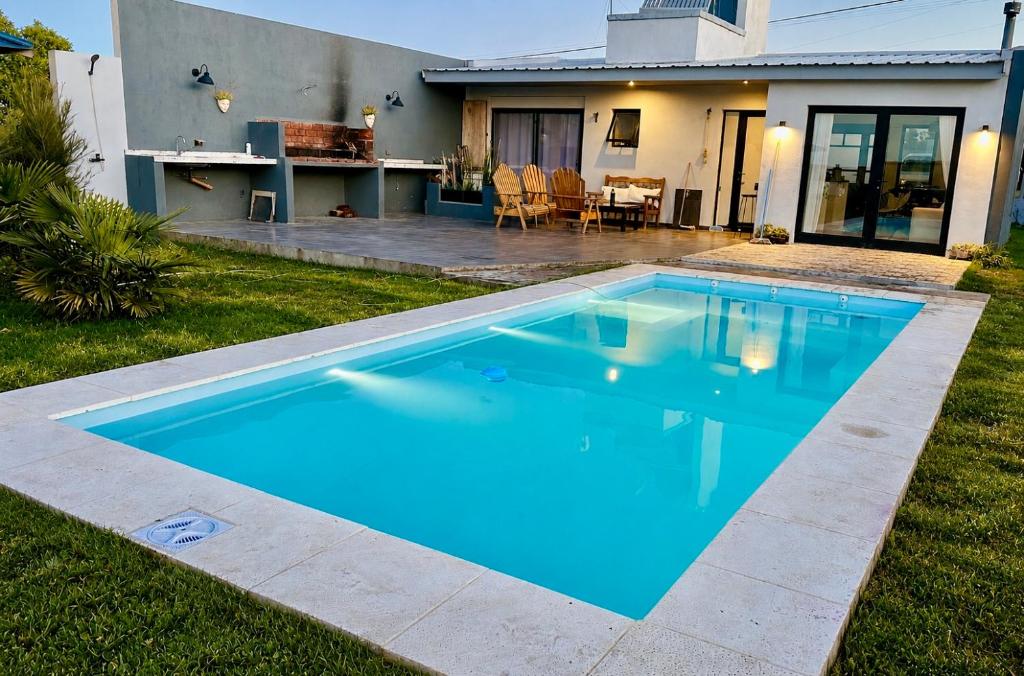 a blue swimming pool in front of a house at Casa Otarina Chapadmalal in Chapadmalal
