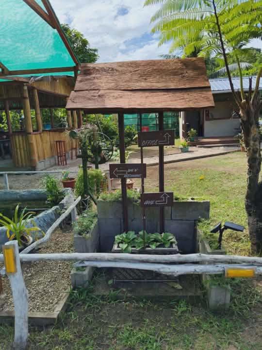 a garden with signs in front of a building at Fortunate Lodge, Restaurant & Bar in Loonékiyawileung