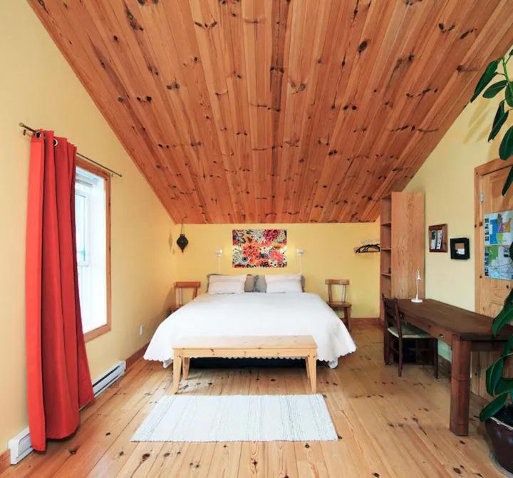 a bedroom with a bed and a wooden ceiling at Spa Stukely in Eastman