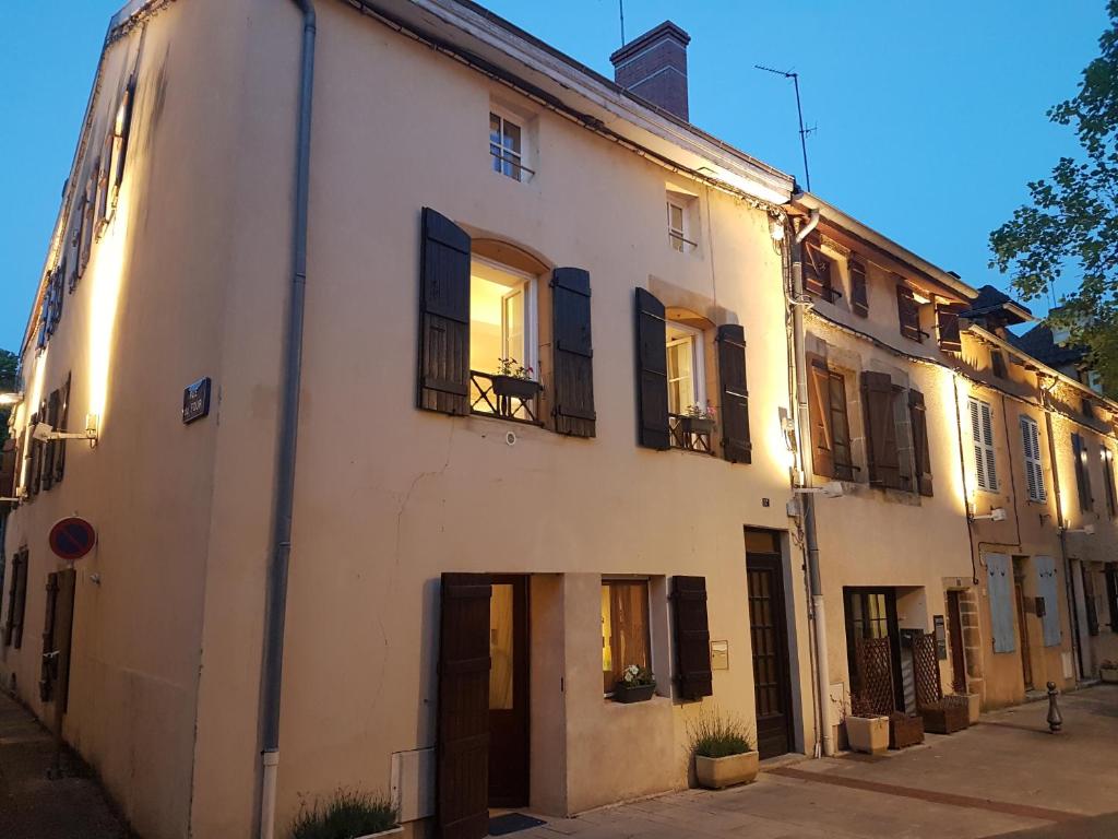 a white building with black shutters on a street at Maison Corcovado in Paray-le-Monial
