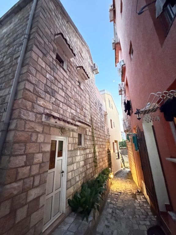 an alley in an old stone building with a white door at ADM Apartment in Bečići