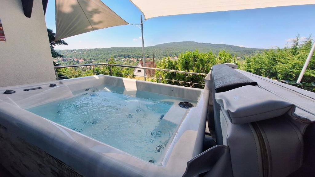 a hot tub on a balcony with an umbrella at Hillside Cottage in Pécs
