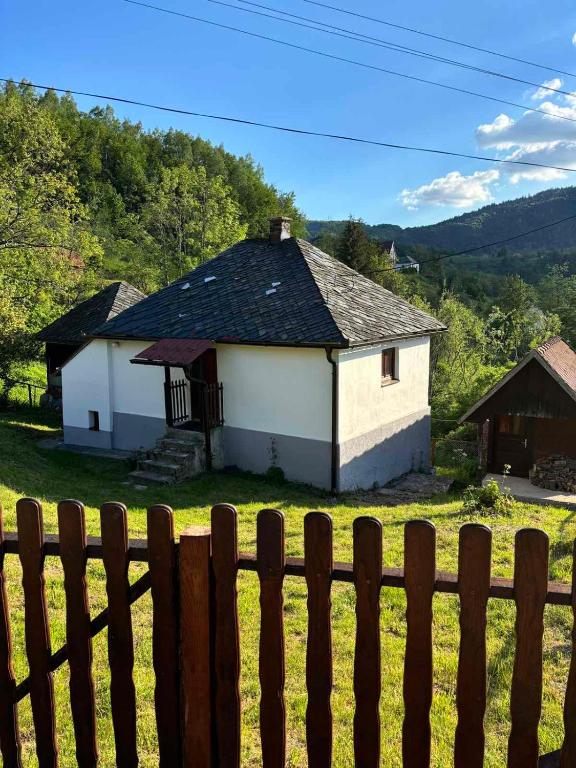 a small white house behind a wooden fence at Etno kuća Močioci in Ivanjica