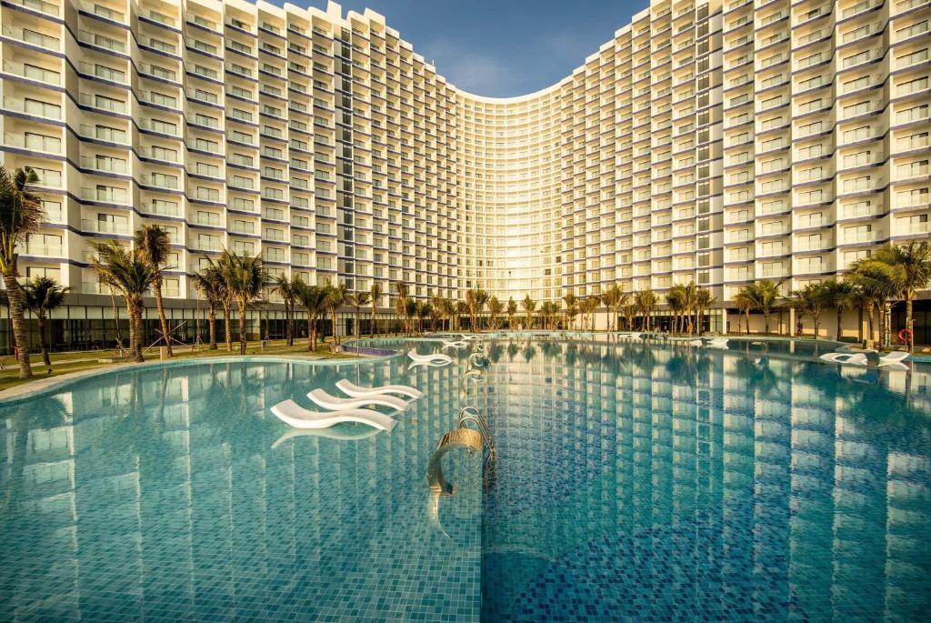 a large swimming pool in front of a large building at Hanna Seaview Stella - The Arena Resort in Cam Ranh International Airport
