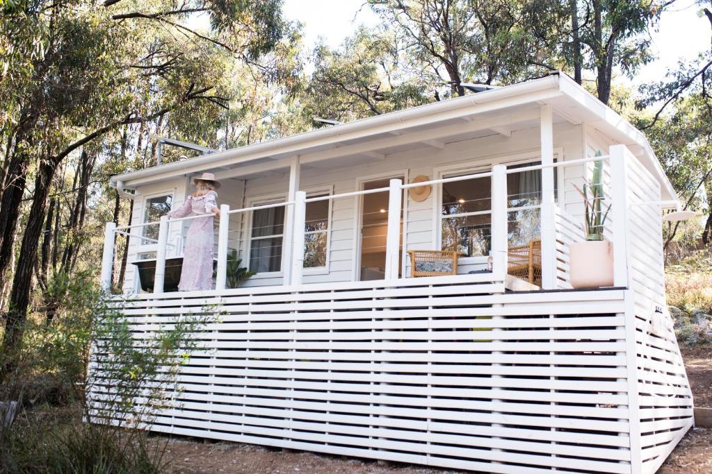 a woman standing on the porch of a white tiny house at ROSINA Beach Shack in Bellbrae