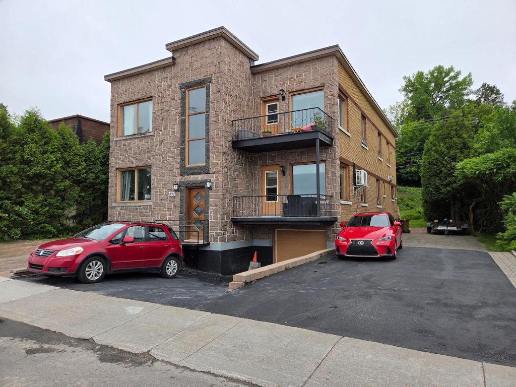 two cars parked in a parking lot in front of a building at Martin's apartment in Saguenay