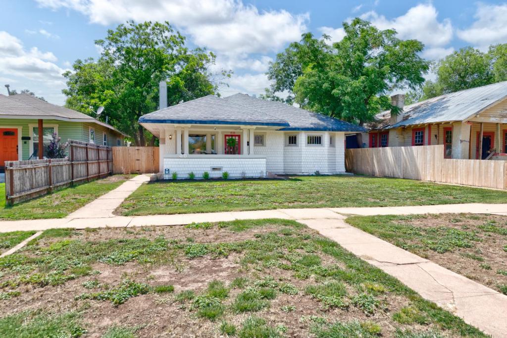 a white house with a fence in a yard at Uptown Merchant in Abilene