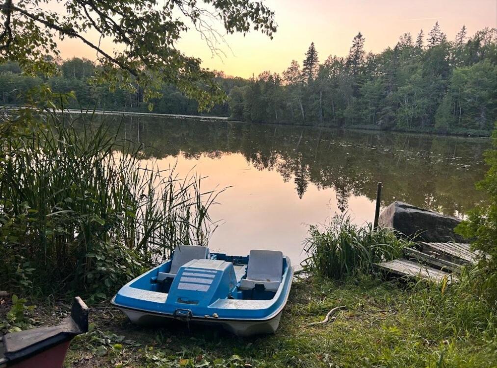 a blue boat sitting on the shore of a lake at Countryside studio on a lake in Bic