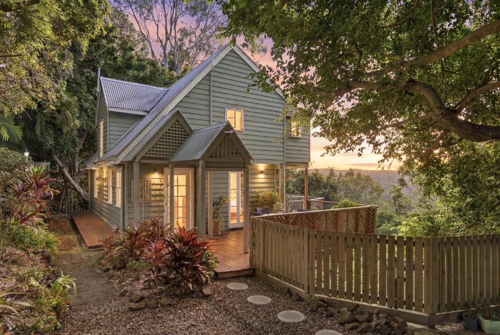a house with a wooden fence in front of it at Misty Valley Cottage in Mapleton