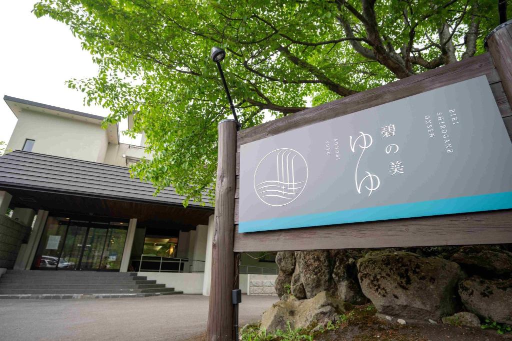 a sign in front of a building at Biei Shirogane Onsen AONOBI YUYU in Biei