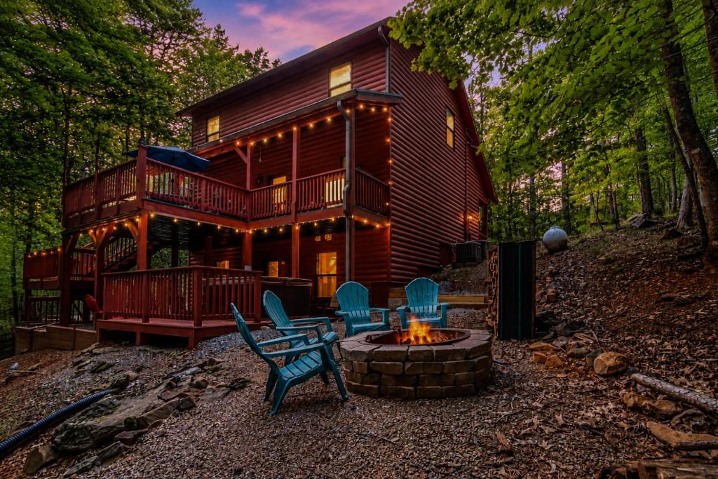 a log cabin with a fire pit and chairs at Quiet mornings and golden hour views welcome to our woodland sanctuary Deer Watch Retreat in Ellijay
