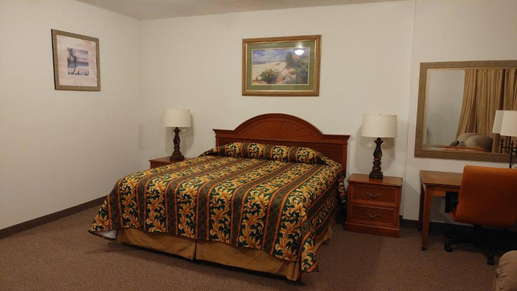 a bedroom with a bed and a desk and a mirror at Country Regency Inn & Suites in Manvel