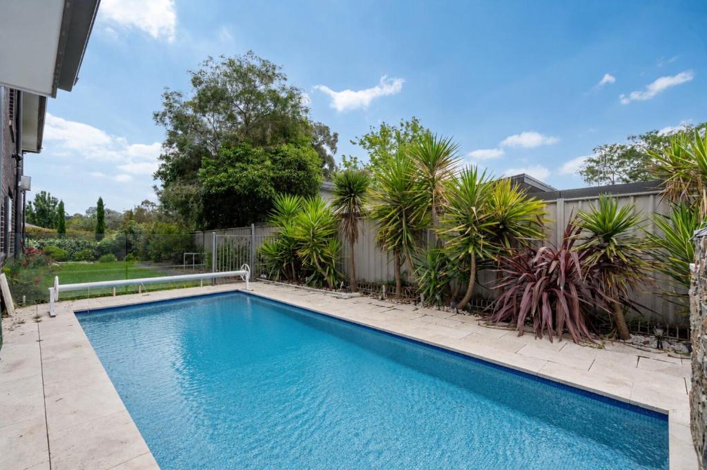 a swimming pool in a yard with palm trees at Charming 3-Bed Getaway with Pool & Garden Oasis in Lyons