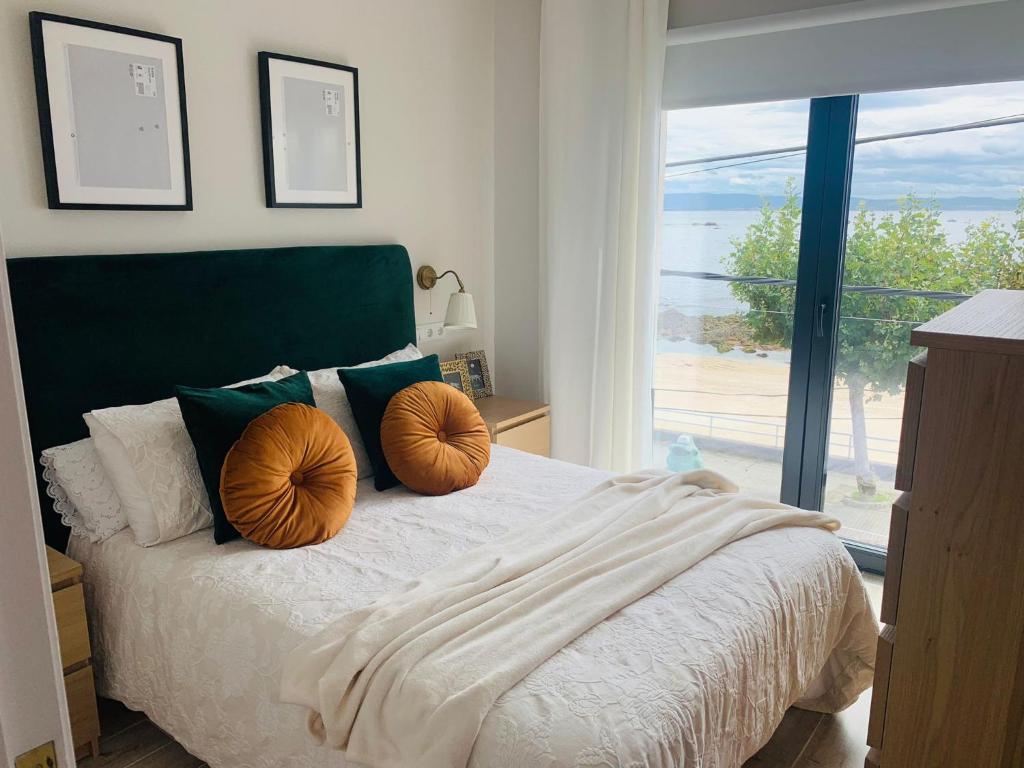 a bedroom with a bed with two orange pillows on it at Casa da Fonteseca a pie de playa in Ribeira
