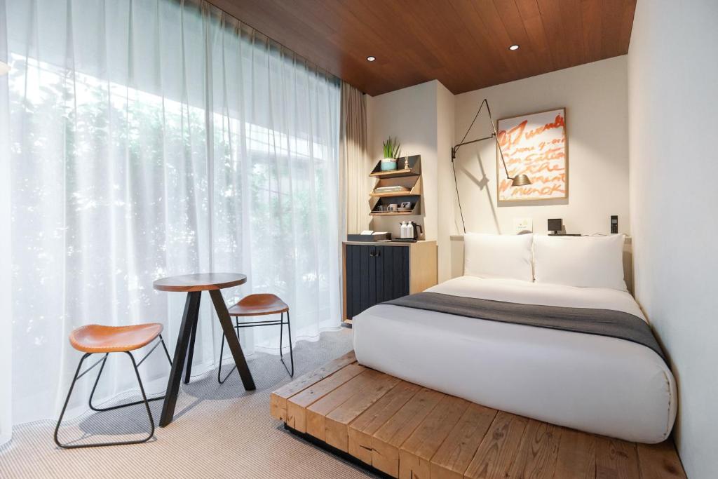 a bedroom with a bed and a table and a window at TRUNK(HOTEL)CAT STREET in Tokyo