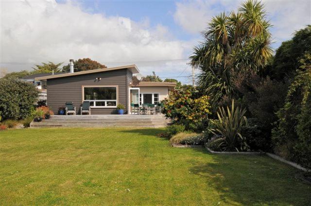 a small house with a large yard with a lawn at Te Moana Delight in Waikanae
